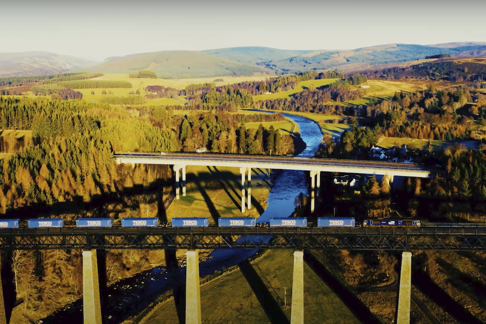 Tesco train on the Highland Main Line crossing a bridge with the A9 in the background